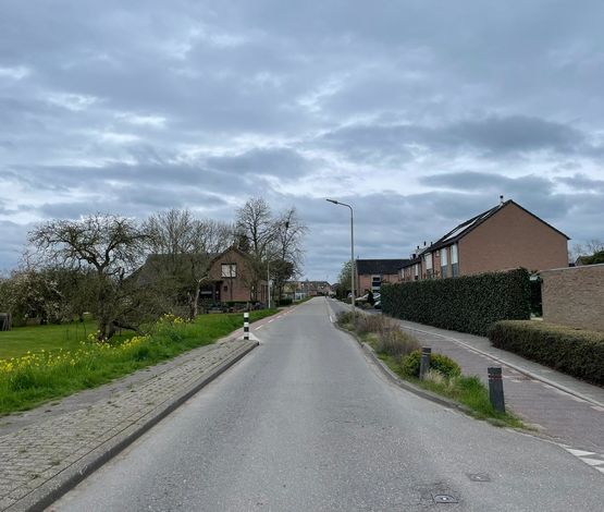 De Kerkweg in Leerbroek richting het dorp met zicht op fietspad, wegversmalling en huizen aan weerszijden.