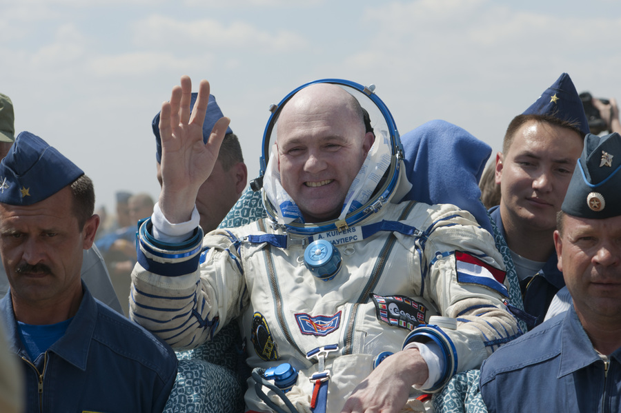 Afbeelding van André Kuipers die na een ruimtereis gedragen wordt door ESA NASA medewerkers