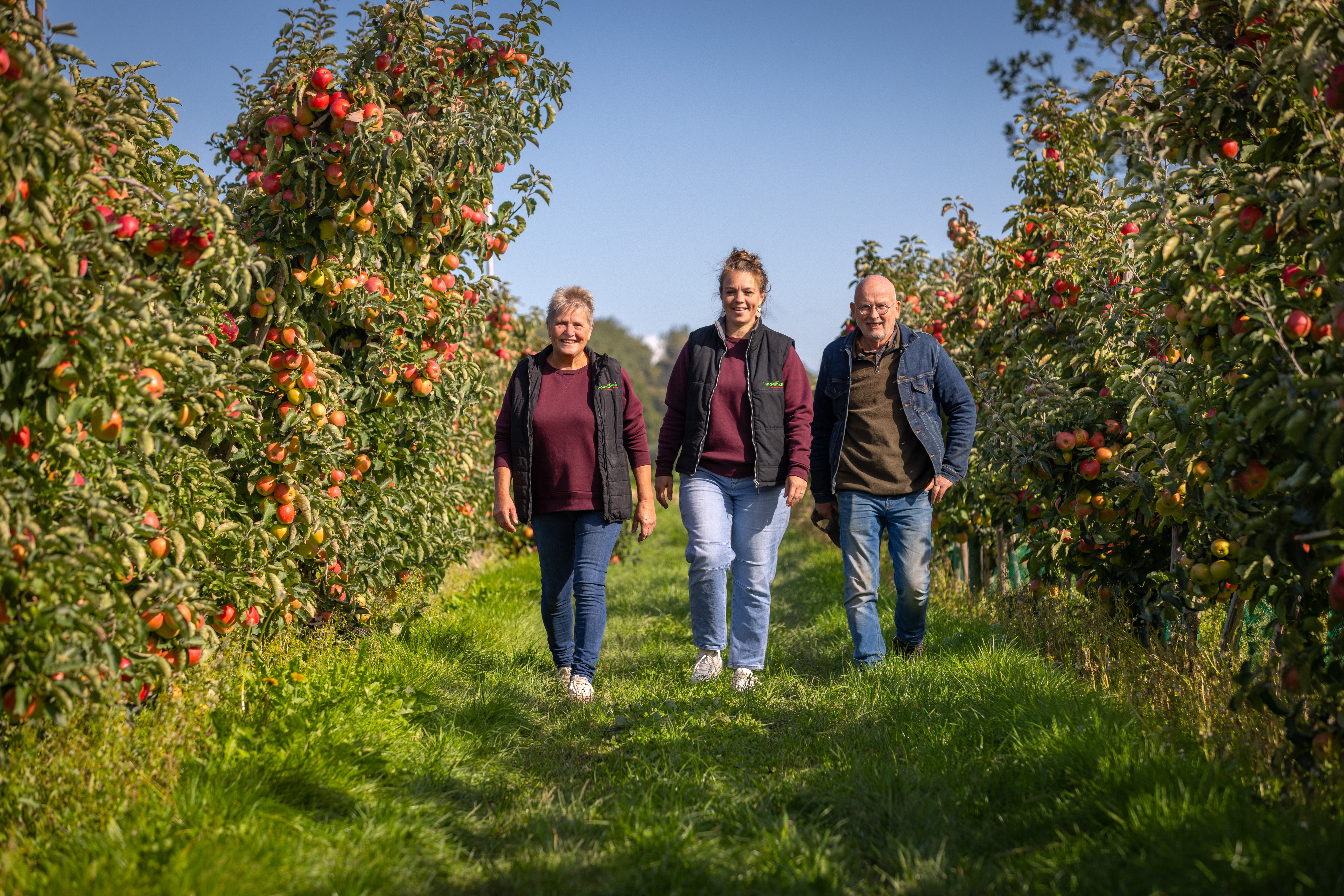 Drie leden van de familie Van Buuren wandelend door de boomgaard